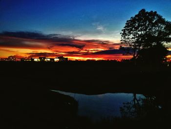 Silhouette trees against dramatic sky during sunset