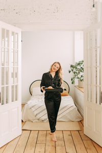 Portrait of smiling young woman standing on wooden floor