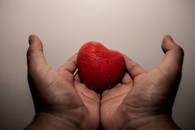 Close-up of hand holding heart shape over white background