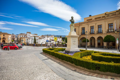 Street by buildings in city against sky