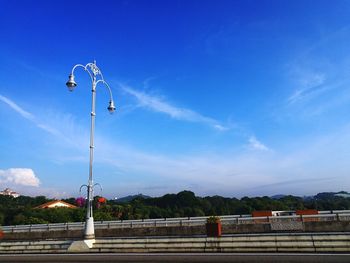 Street light by railing against blue sky