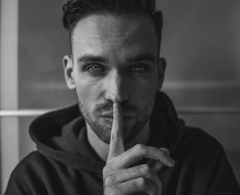 Close-up portrait of young man with finger on lips