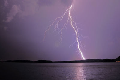 Lightning over sea against dramatic sky