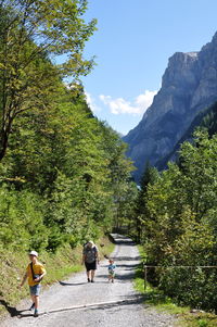 Rear view of people walking on mountain road