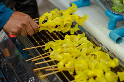 Cropped hand of person roasting food on barbecue grill