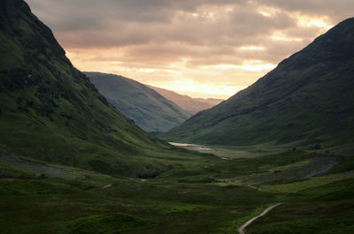 Scenic view of mountains against cloudy sky during sunset