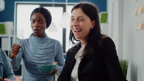 Portrait of smiling young woman standing in office