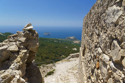 Scenic view of cliff by sea against clear sky