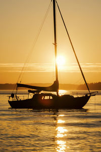 Silhouette boat sailing on sea during sunset