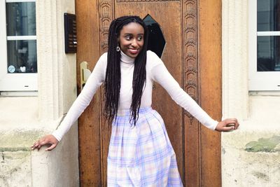 Portrait of smiling young woman standing against building