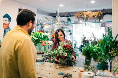 Rear view of man with woman holding bouquet at store