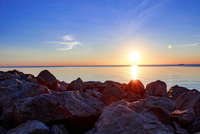 Rocks on shore against sky during sunset