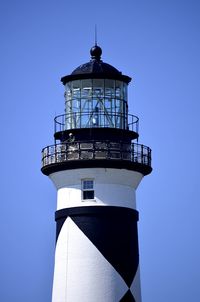 Low angle view of lighthouse against building against clear sky