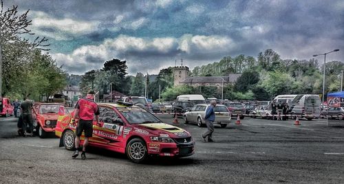 Cars on road against cloudy sky