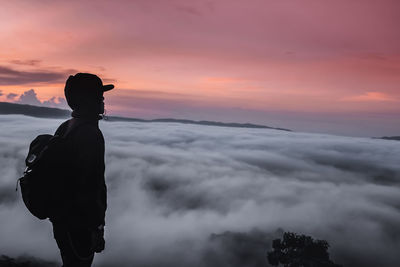 Side view of silhouette man standing on mountain against sky during sunset