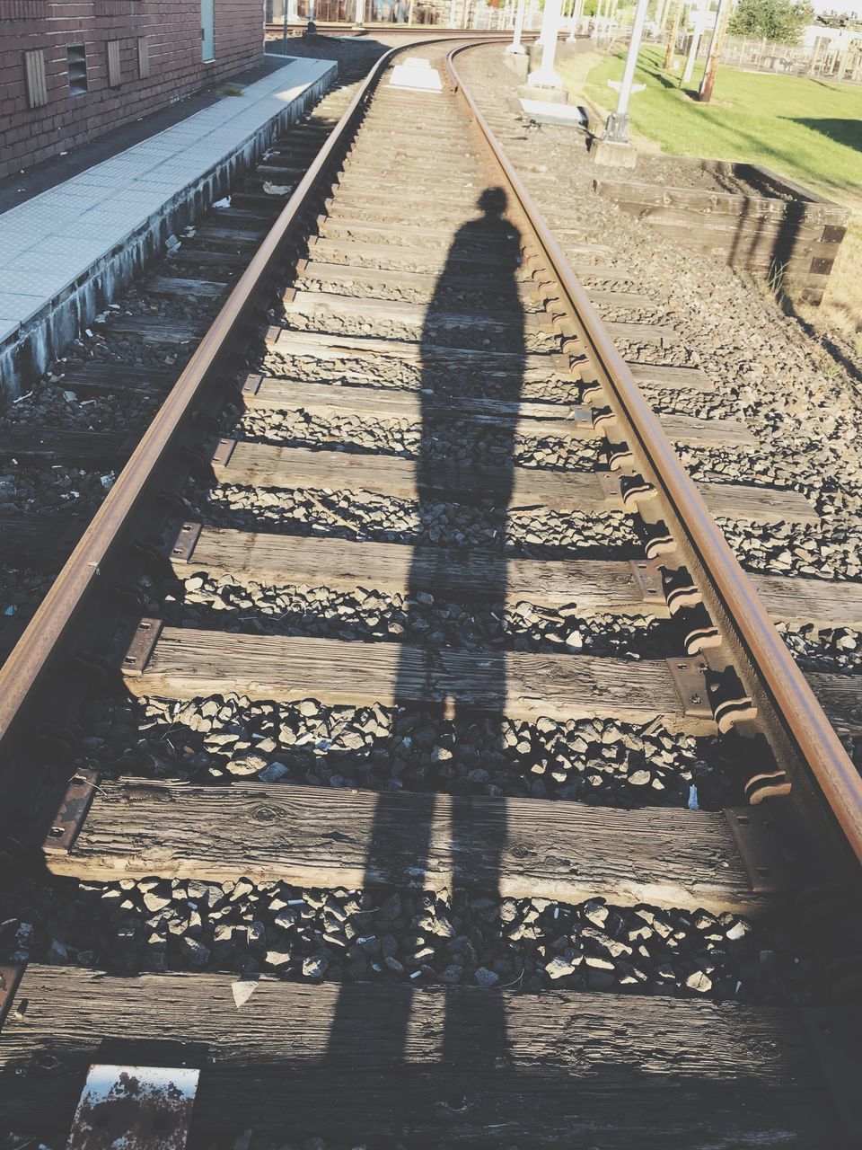 SHADOW OF MAN ON RAILROAD TRACK