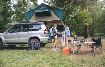 Friends standing by car in forest