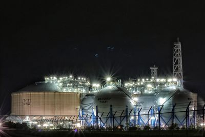 Illuminated factory against sky at night