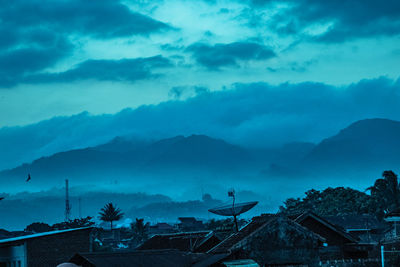 Scenic view of houses and mountains against sky at dusk