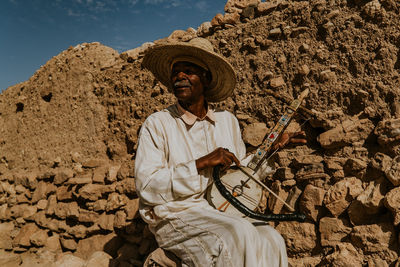 Man holding umbrella while sitting outdoors