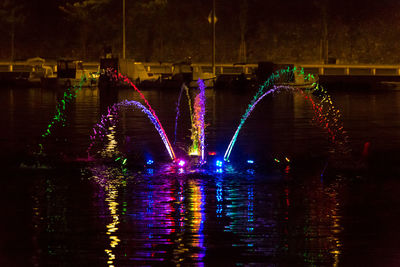 Illuminated city by river at night