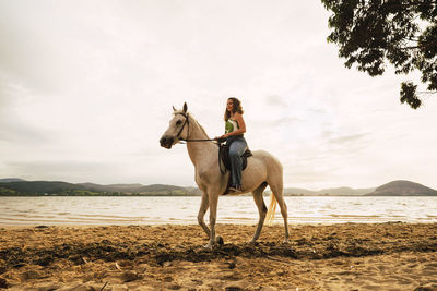 Young woman riding horse at waterfront