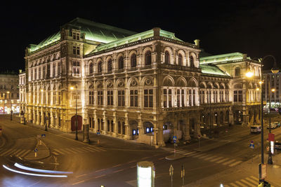 Road against illuminated building at night