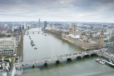 Bridge over thames river against cloudy sky