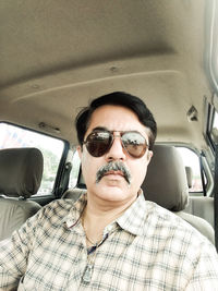 Portrait of man wearing sunglasses sitting in car