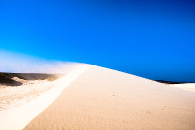 Scenic view of desert against clear blue sky