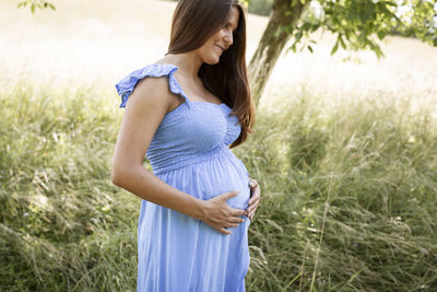 Smiling pregnant woman in meadow