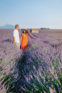Couple holding hands standing at flowering field