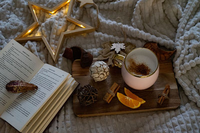 Christmas decorations with lights, hot drink, fruits and a good book