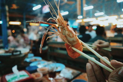 Cropped hand holding prawn in restaurant