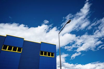 Low angle view of street light by building against cloudy sky