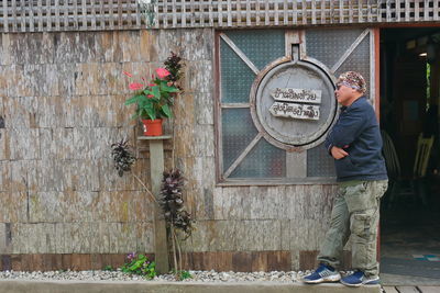 Man holding umbrella standing by wall of house