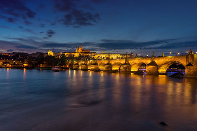 Illuminated bridge over river against sky at night