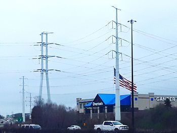 Electricity pylon by road against sky