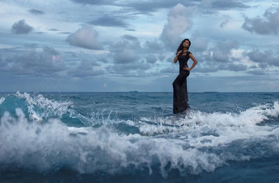 Young woman in sea against sky