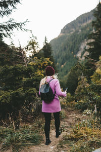 Rear view of woman standing on road amidst trees