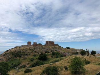 Castle on mountain against cloudy sky