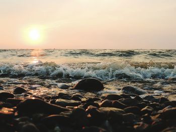 Close-up of waves on beach against sky during sunset