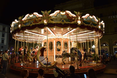 People at amusement park against clear sky at night