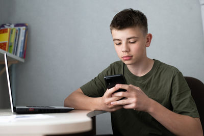 Teenage boy using smartphone for study or communication, looking at mobile screen