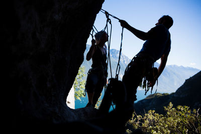 Silhouette men on rock against sky