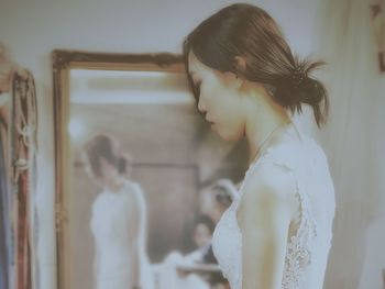 Side view of bride standing by mirror at home
