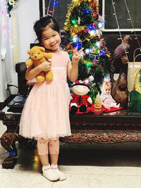 Full length of girl standing by christmas tree