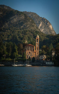 Buildings by river against sky