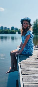 Portrait of young woman sitting on pier over lake