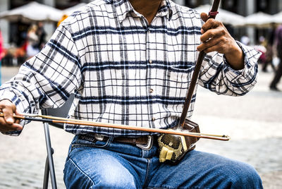 Midsection of man holding string instrument